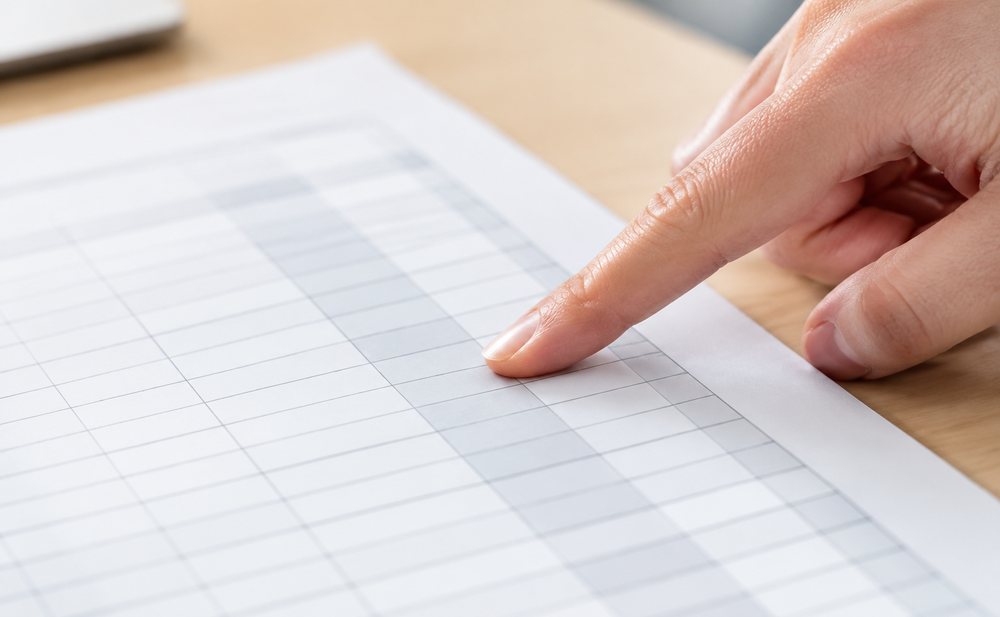 手指点在纸质表格的一列数字上,纸面有淡淡的格线